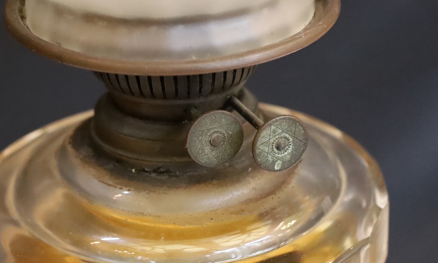 An Edwardian brass oil lamp with cut glass reservoir and pink tinted etched glass globe and flue, height overall 65cm